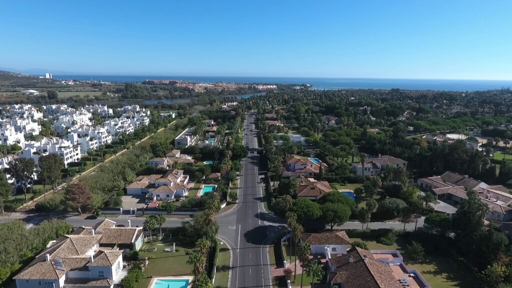Aerial perspective of luxury Mediterranean villas and lush greenery overlooking the coastline in Sotogrande.
