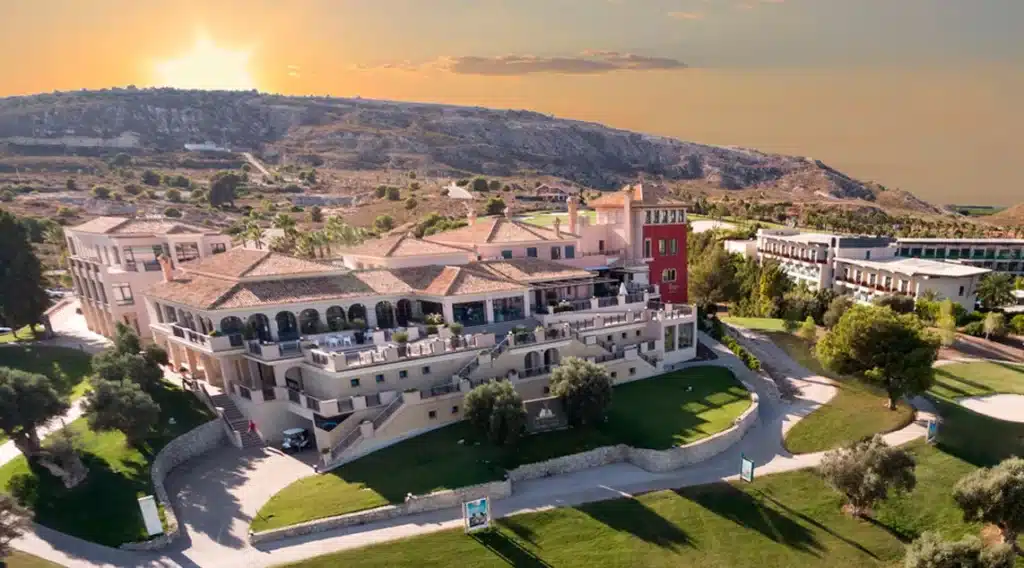 Aerial view of the Mediterranean-style clubhouse in La Finca featuring tiered terraces and sunset lighting over the golf course.