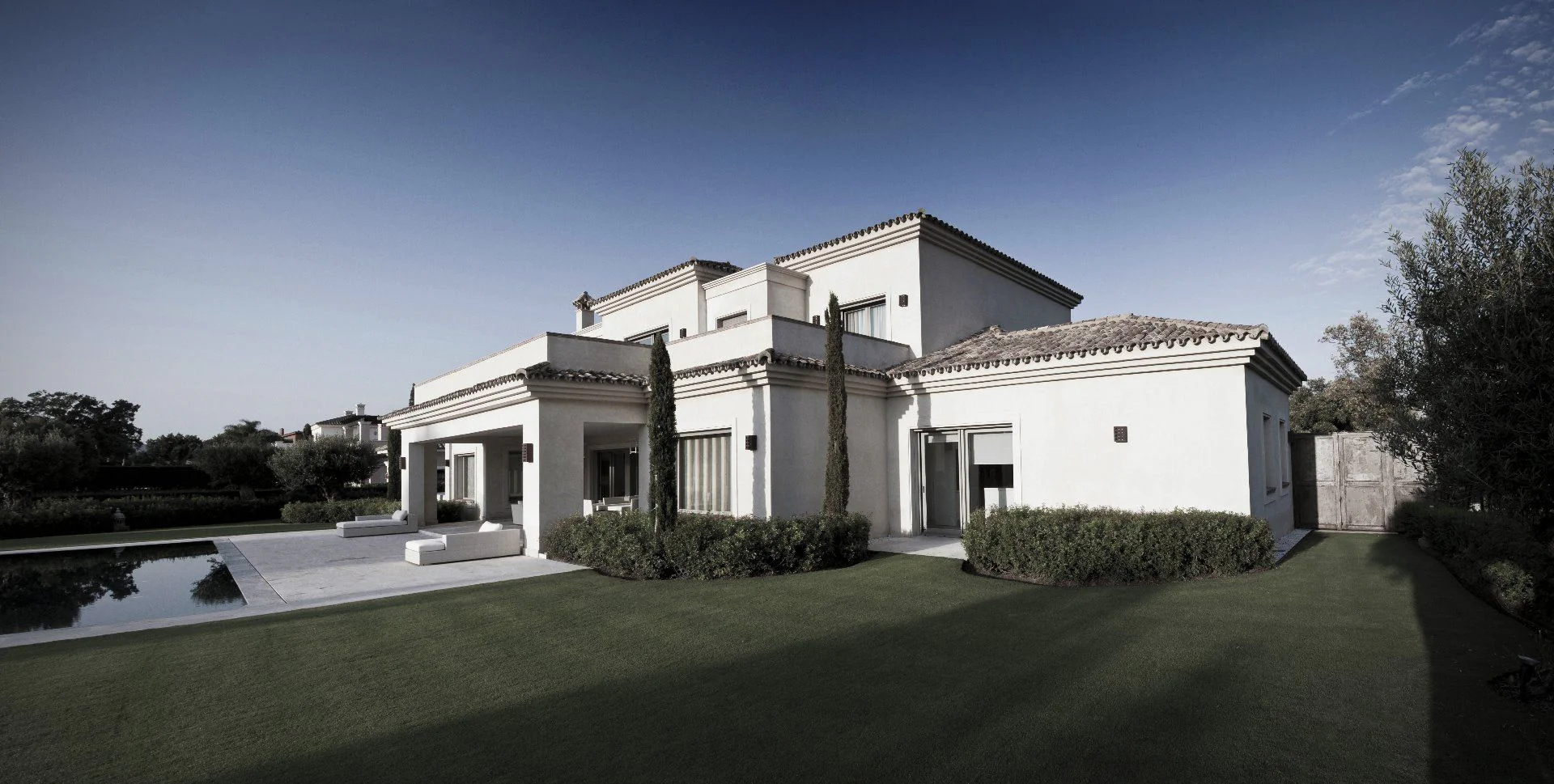Symmetrical luxury villa entrance featuring clean white lines and manicured Mediterranean landscaping.