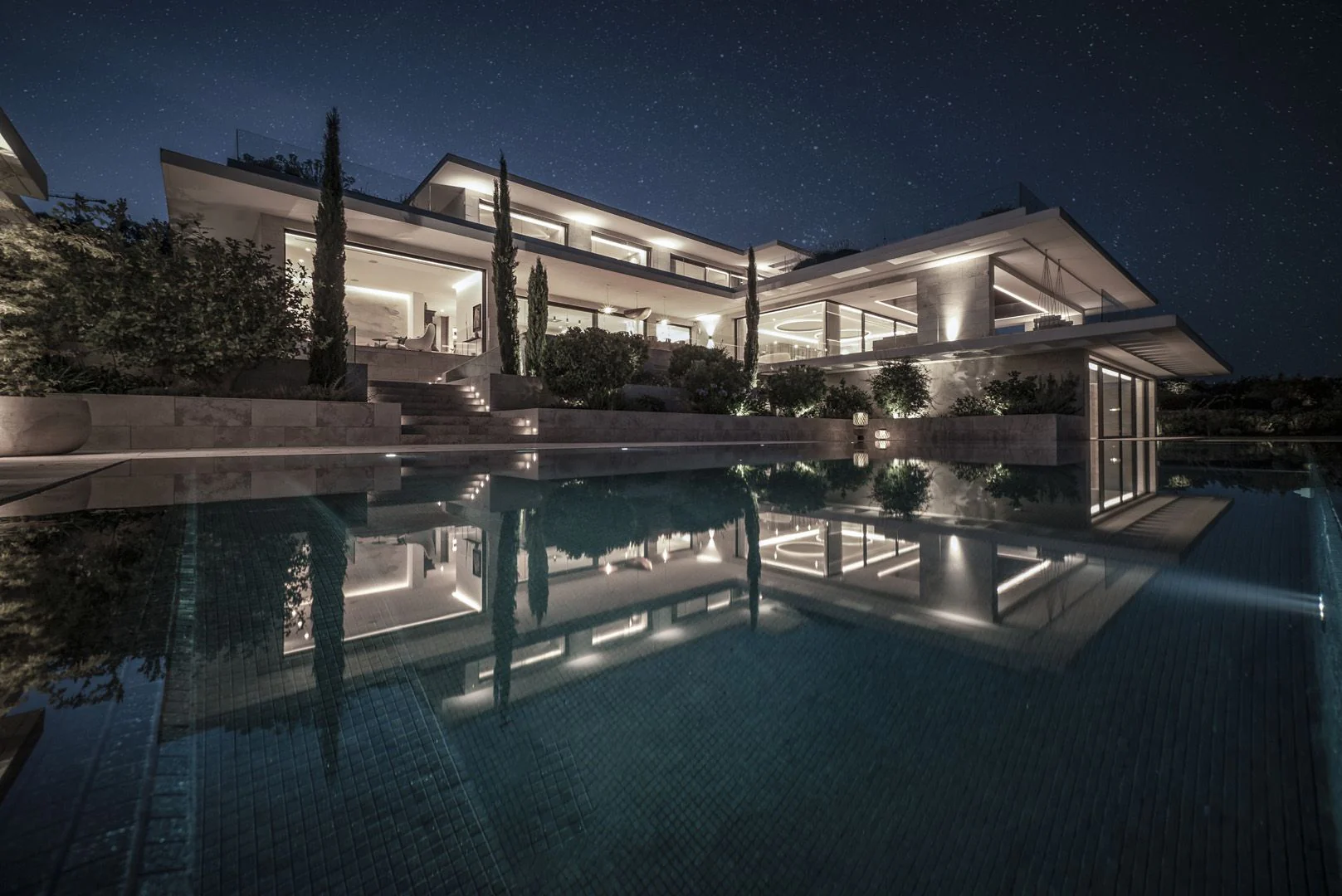 Close-up of a minimalist infinity pool with submerged steps and a perimeter overflow system blending with the horizon.