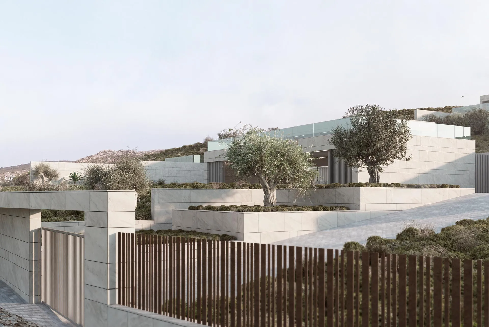 Exterior view of a luxury villa with travertine stone walls, olive trees, and integrated landscaping in a Mediterranean hillside.