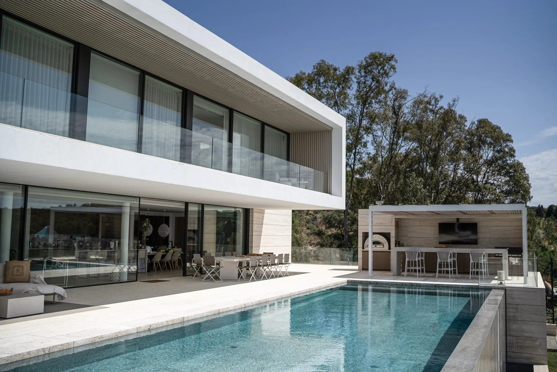 Modern luxury villa entrance featuring a minimalist white facade, manicured gardens, and natural stone pathways in Marbella.