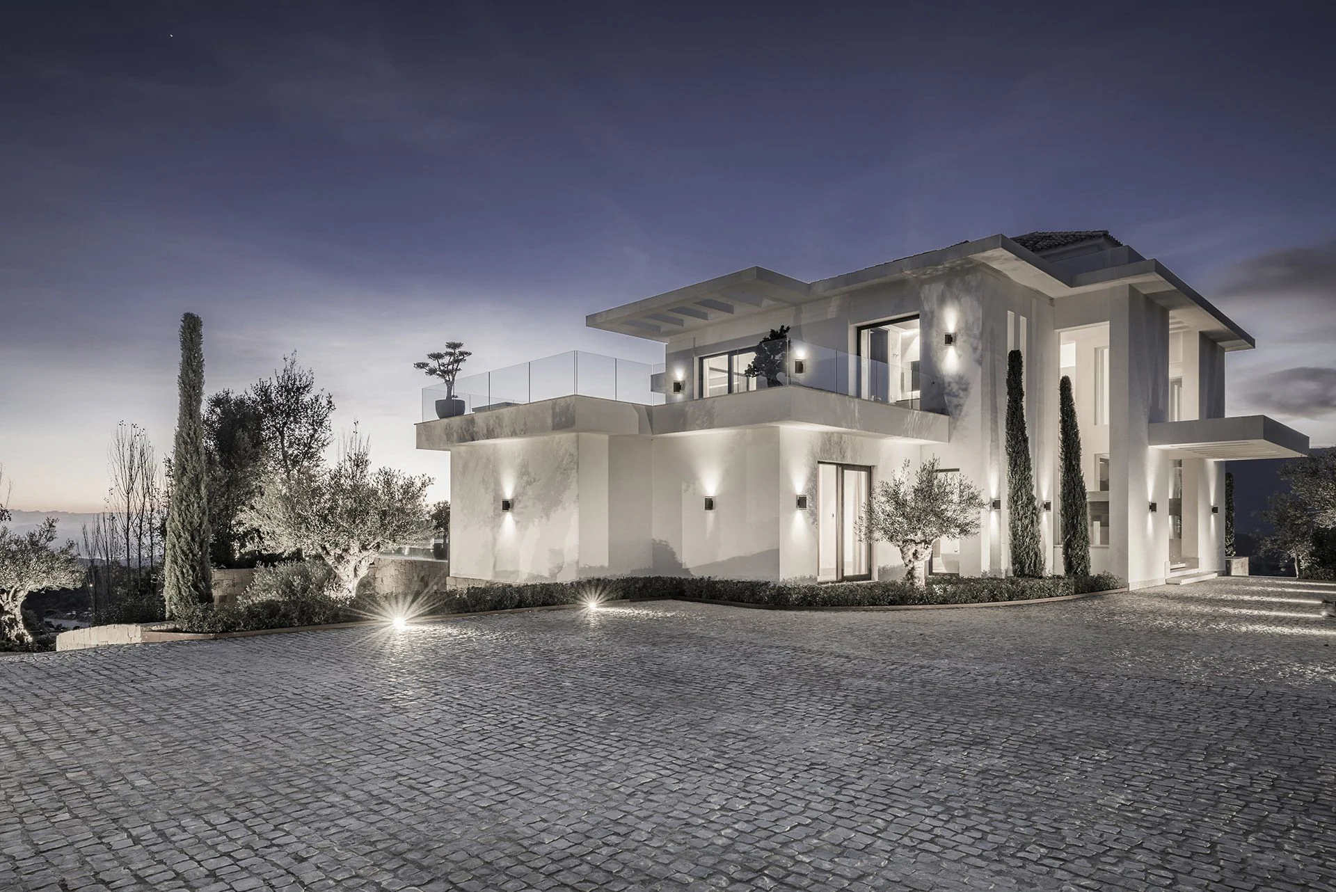 Exclusive driveway with cobblestone paving and warm facade lighting designed by Manuel Ruiz Moriche.