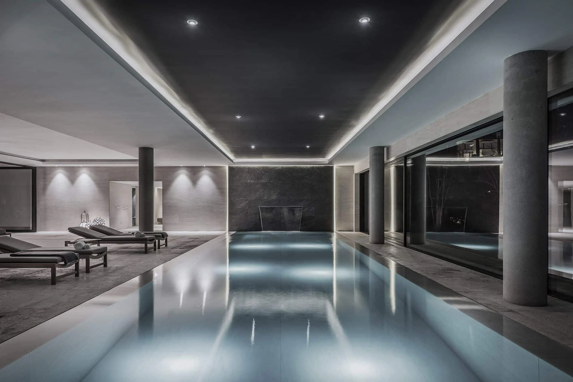 Sophisticated indoor heated pool area with natural stone finishes and ambient lighting.