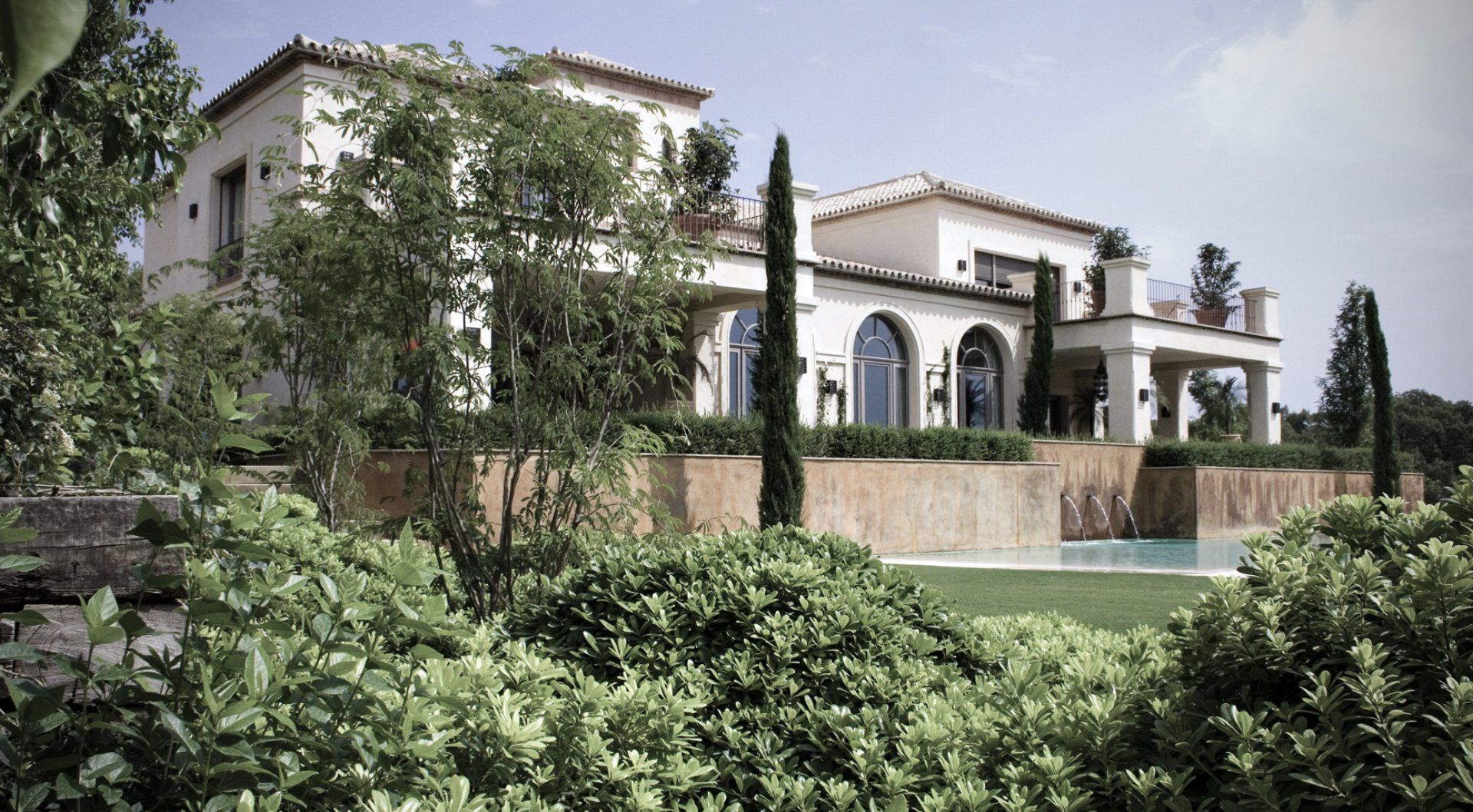 Perspective of a minimalist white villa with large floor-to-ceiling windows overlooking the golf course landscape.