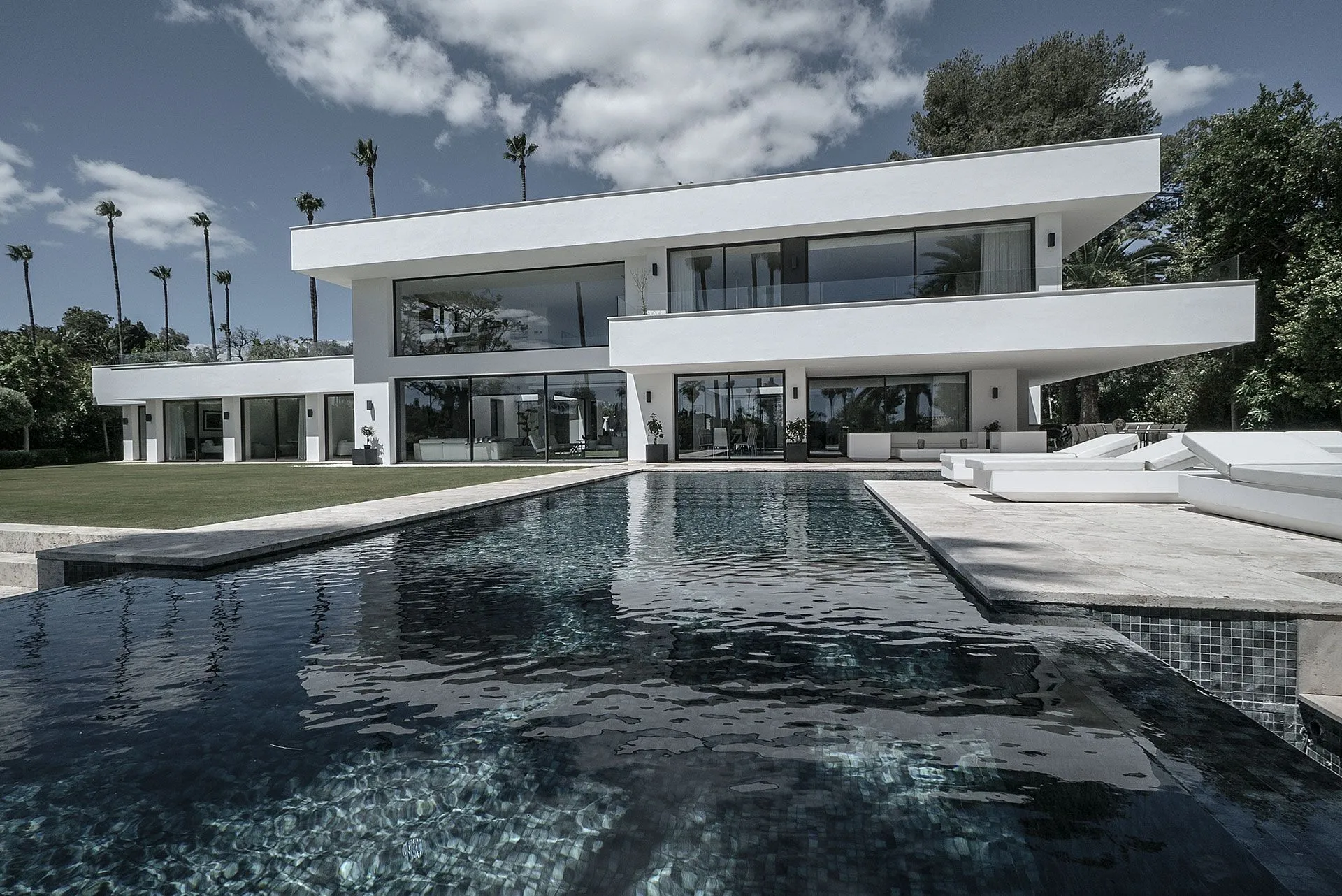 Modern white villa with expansive glass facades and reflecting pool in the exclusive area of Sotogrande.