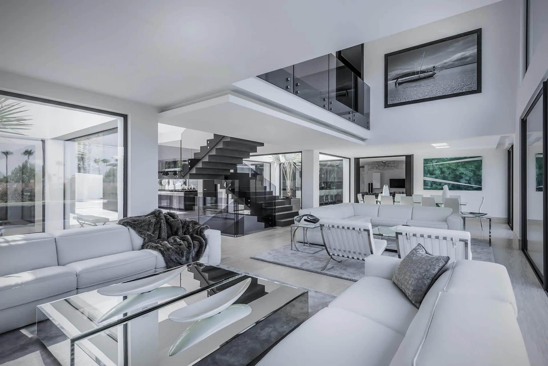 Sophisticated double-height living room with glass gallery, designer furniture, and architectural staircase by Manuel Ruiz Moriche.