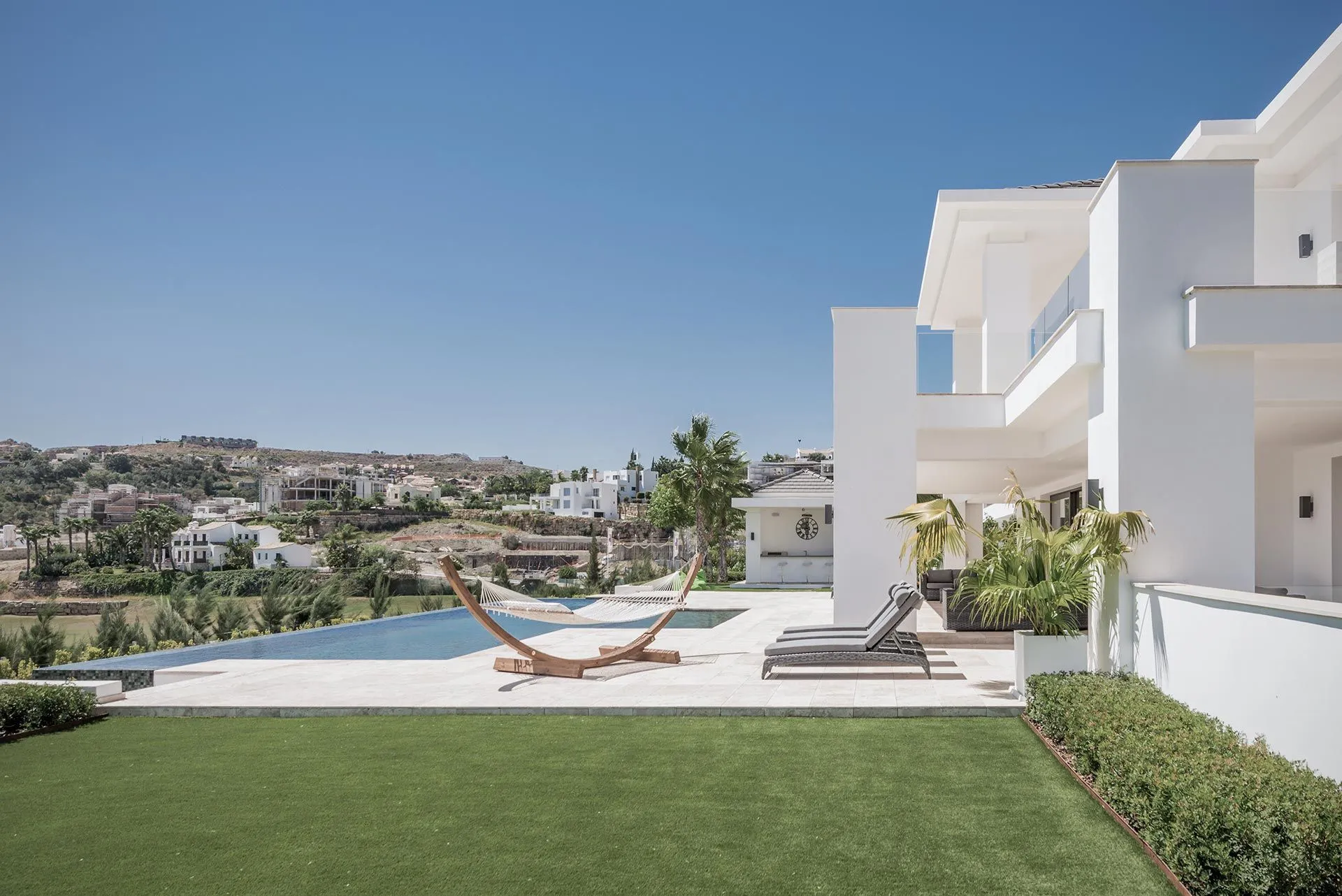 Expansive outdoor lounge area with contemporary white architecture and Mediterranean landscaping.