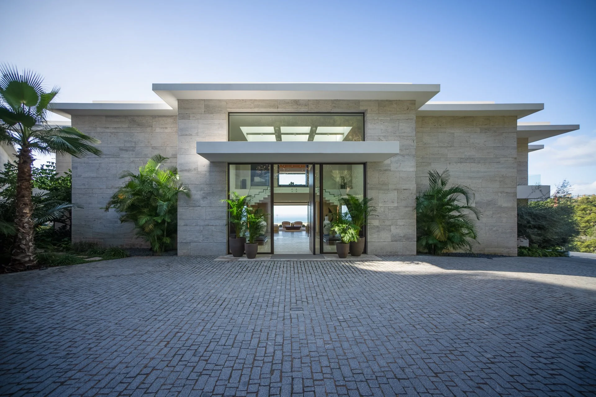 Modern villa entrance with textured stone walls and minimalist landscaping by ARK Architects.