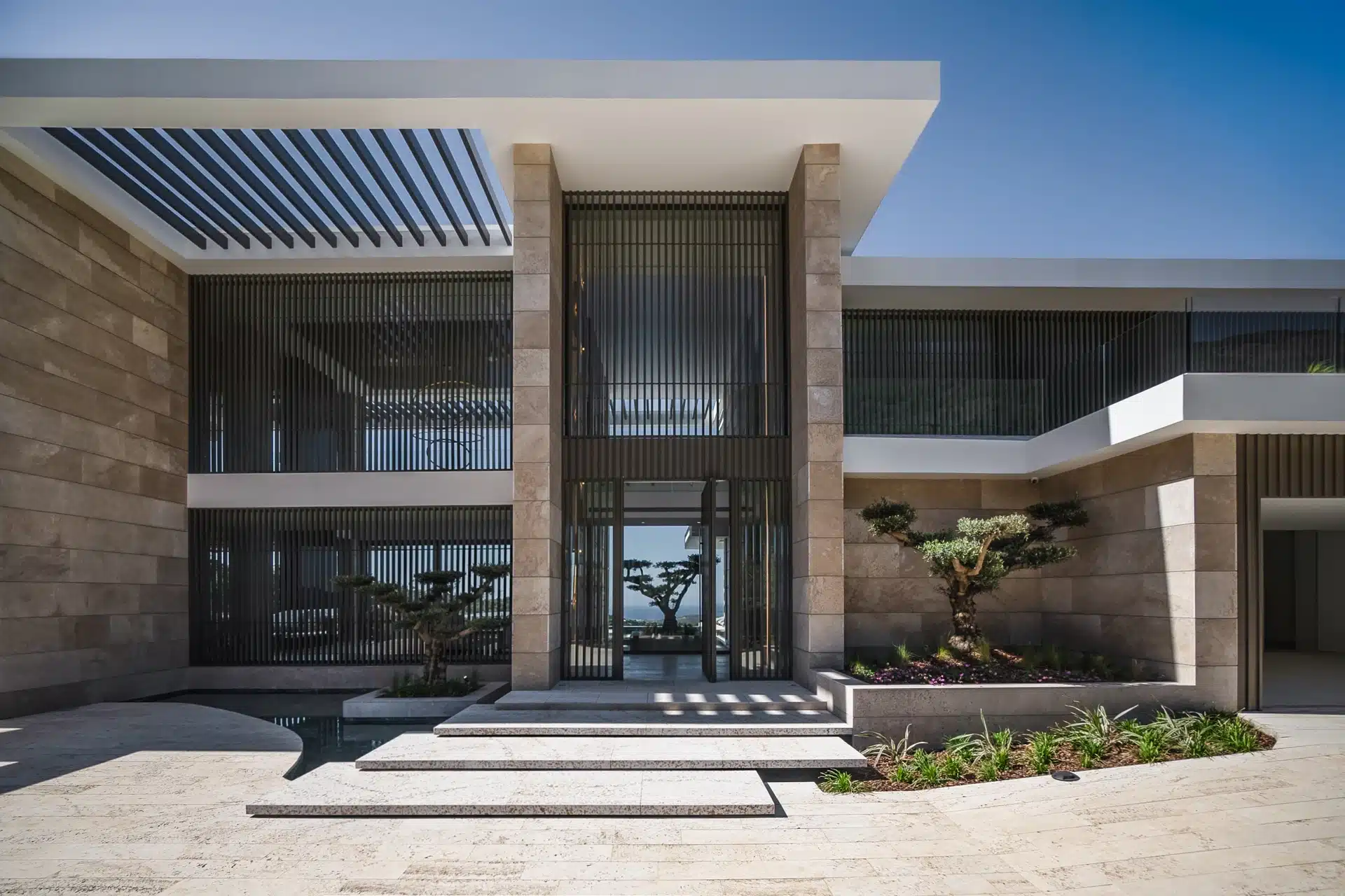 Main entrance of Villa Kaizen featuring a monumental pivot door and minimalist landscaping.