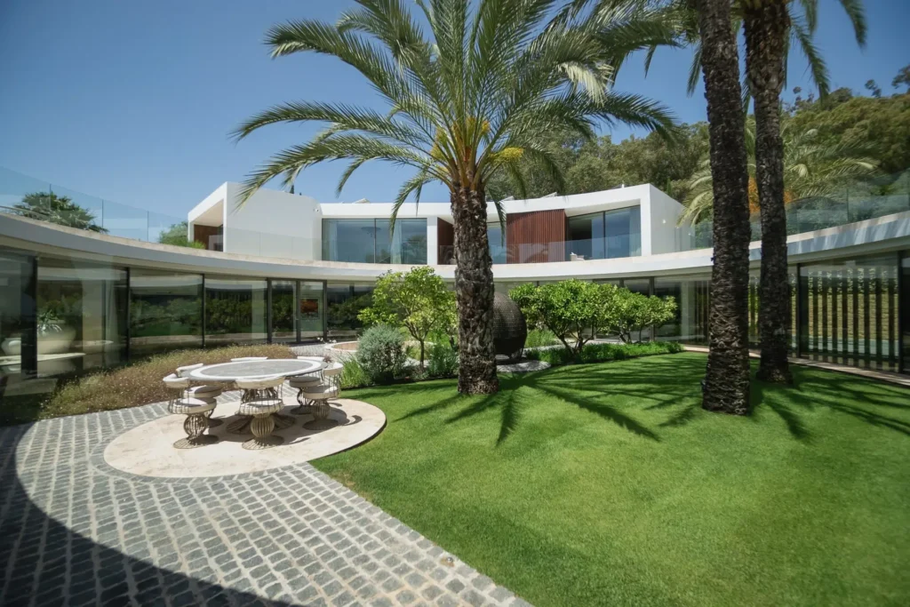Organic curved facade and garden with outdoor seating area at Villa Aquarius, a luxury residence in Sotogrande by Manuel Ruiz Moriche (ARK Architects).