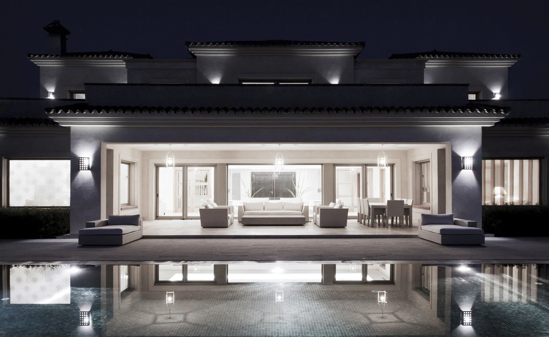 Contemporary villa facade at night with warm integrated lighting by ARK Architects in San Roque.
