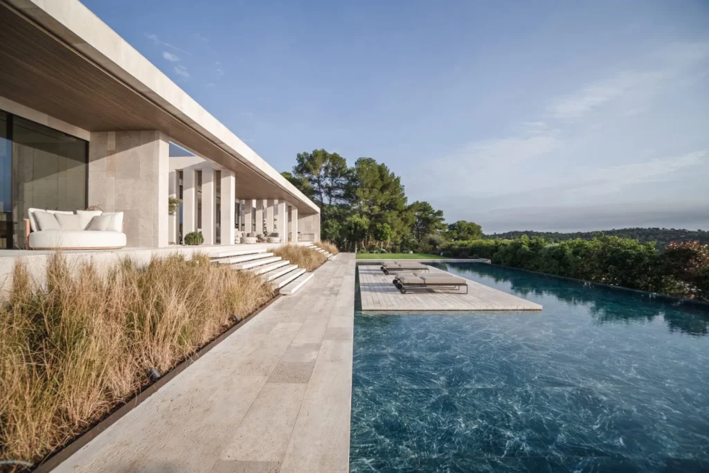 Contemporary villa exterior featuring a seamless infinity pool with turquoise water overlooking the Mediterranean landscape.