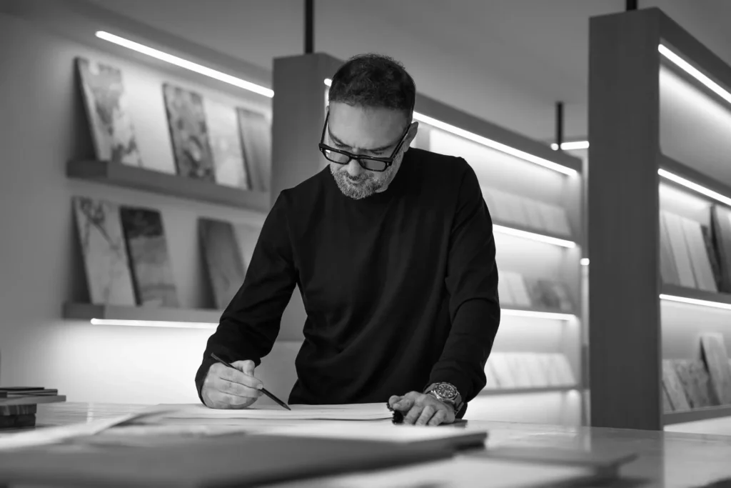 A focused professional sketching designs at a modern workspace, showcasing creativity and architectural expertise.