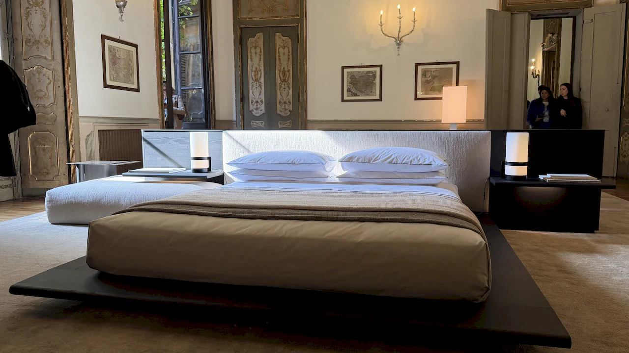 Dormitorio de diseño minimalista con cama de plataforma baja integrada en una estancia palaciega clásica en Milán.