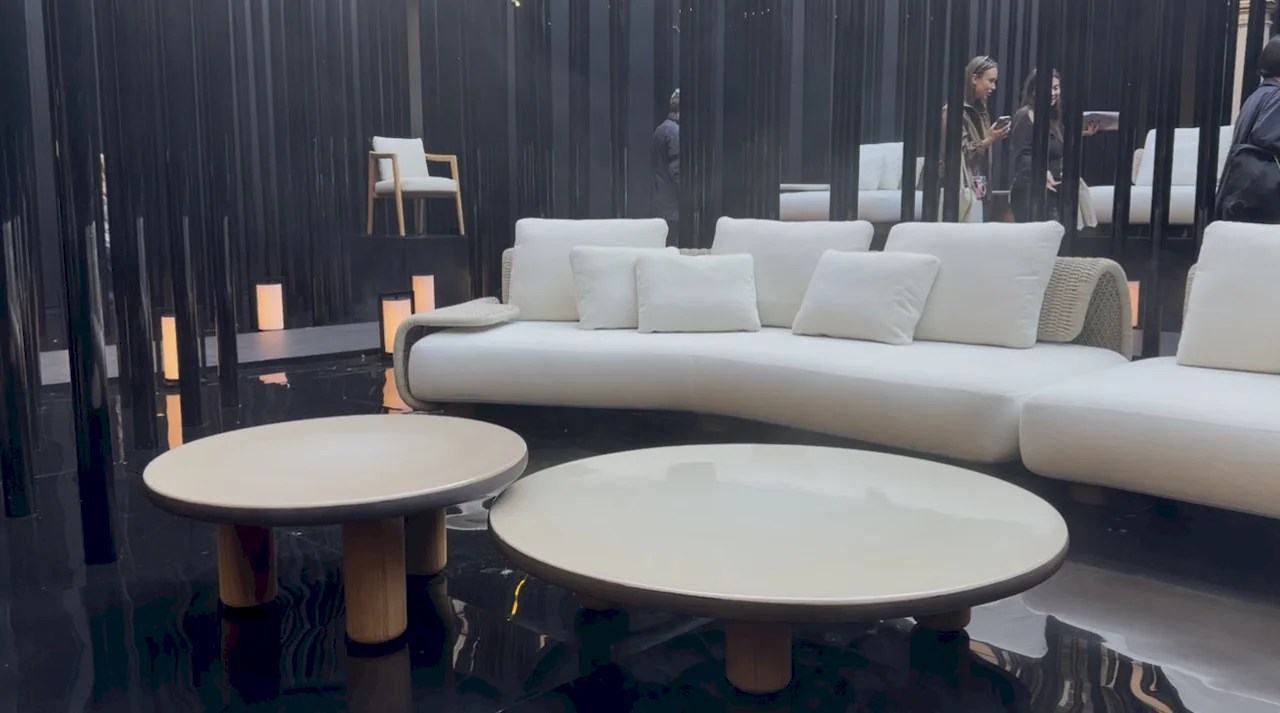 Conjunto de salón vanguardista con sofá curvo blanco y mesas auxiliares circulares sobre suelo técnico brillante.