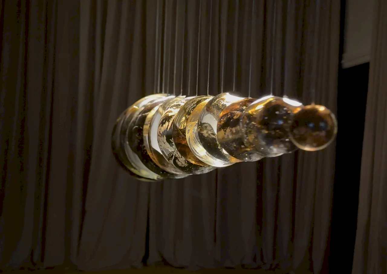 Escultura de iluminación artística suspendida con esferas de cristal y acabados metálicos en la Feria de Milán