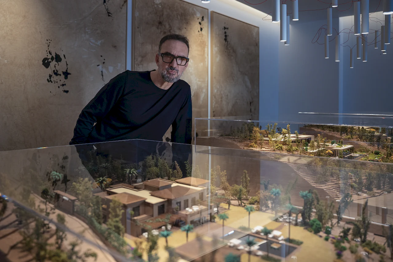 Architect Manuel Ruiz Moriche of ARK Architects stands next to a detailed model of a luxury residential project.