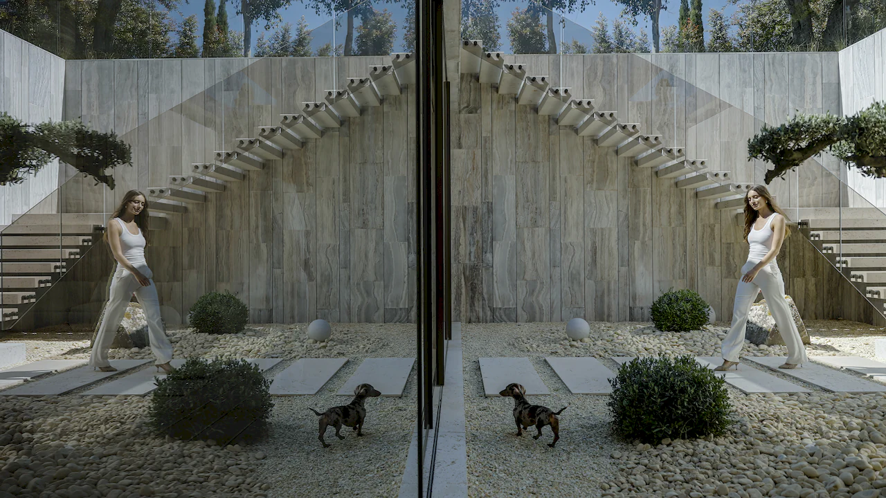 Patio interior de Villa Enso con escalera escultural de piedra, diseño minimalista y reflejos arquitectónicos.