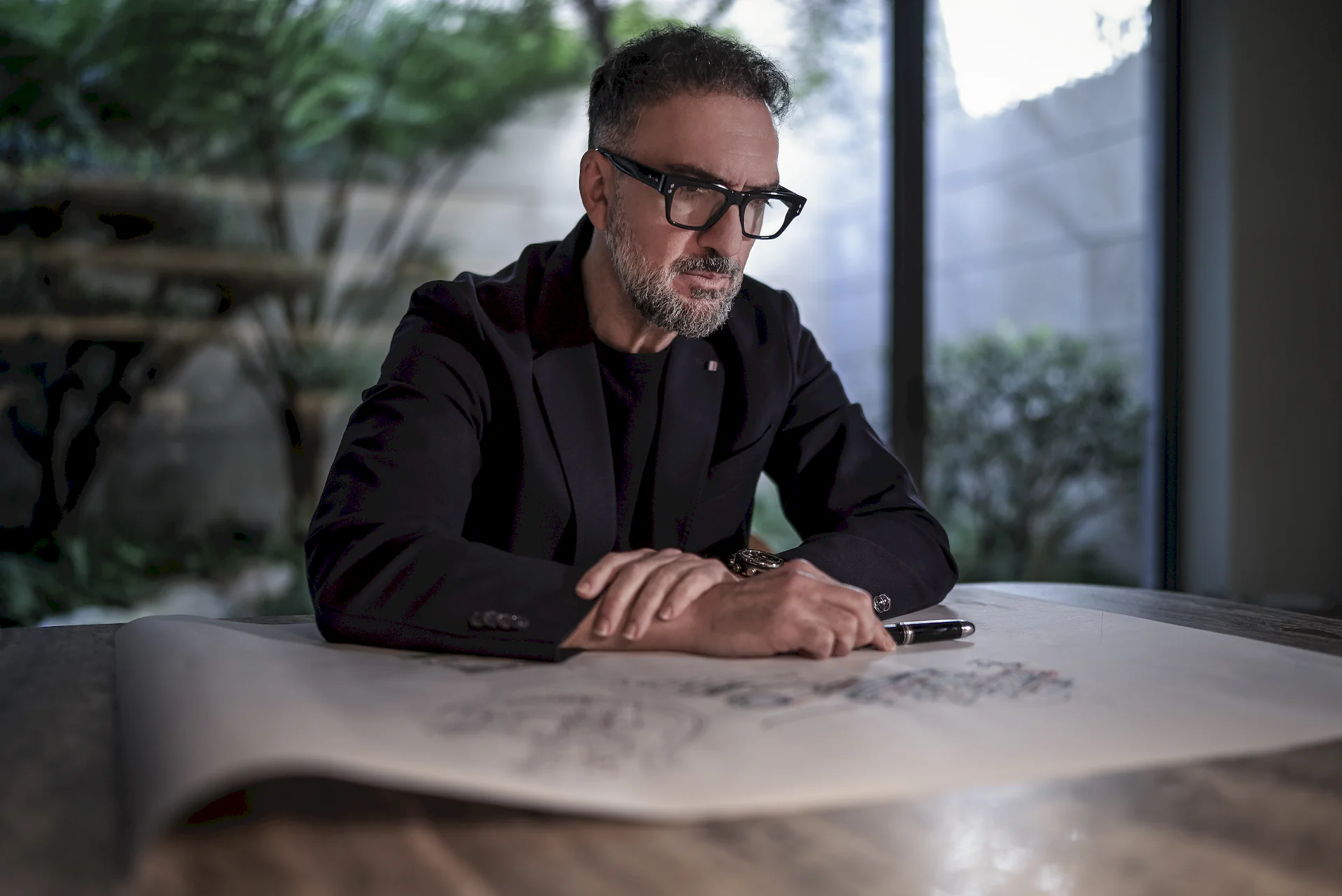 A portrait of Manuel Ruiz Moriche, lead architect at ARK Architects, reviewing a blueprint in his studio.